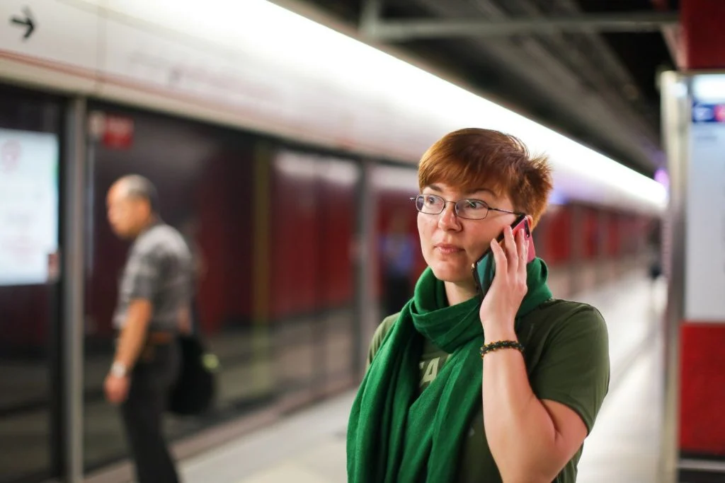 donna al telefono mentre aspetto un treno in ritardo e cerca di capire come chiedere il rimborso